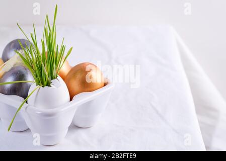 Festive Easter card with homemade painted eggs in a plastic box and fresh green grass on a tablecloth background. Stock Photo