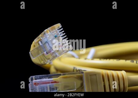 Ethernet cable with RJ45 plugs isolated on a black background. Stock Photo