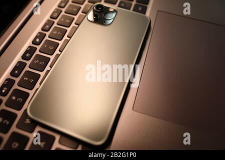 Silver smartphone lie on laptop keyboard in office close-up Stock Photo