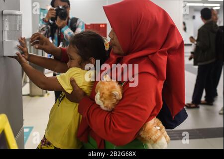 Jakarta, Indonesia. 3rd Mar, 2020. A mother helps her daughter take hand sanitizer at the Mass Rapid Transit station in Jakarta, Indonesia, March 3, 2020. Two Indonesian nationals have been infected with COVID-19 in the country, Indonesian President Joko Widodo said on Monday, marking the first confirmed cases in Indonesia. The president said that Indonesia has been seriously undertaking efforts to counter the spread of the virus, including setting up thermal scanners in 135 gates. Credit: Agung Kuncahya B./Xinhua/Alamy Live News Stock Photo