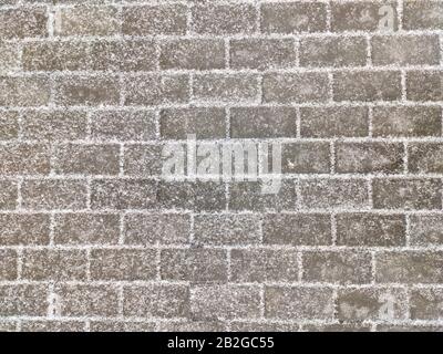 Texture of paving gray rectangular stone tiles covered with light snow. Top view Stock Photo