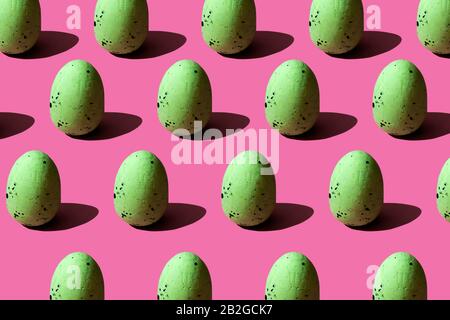 Patter with green quail eggs on pink background, strong light shadows. Easter trendy design Stock Photo