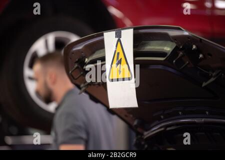 Stuttgart, Germany. 03rd Mar, 2020. A high-voltage warning sign hangs on the hood of a Jaguar I-Pace electric car in a garage. The motor vehicle industry in Baden-Württemberg is demanding financial support from the state for garages in their entry into electromobility. (to dpa 'Motor trade wants subsidies for electric mobility') Credit: Marijan Murat/dpa/Alamy Live News Stock Photo