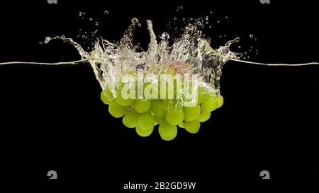 Juicy green grapes splashing into fresh water on black background, panorama Stock Photo