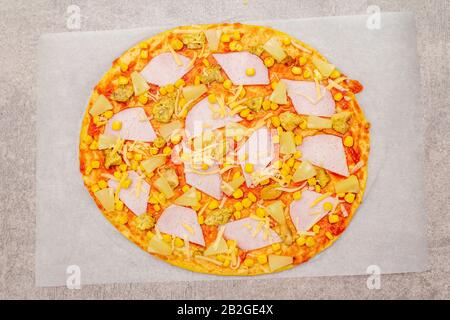Raw Hawaiian pizza on parchment on stone background Stock Photo