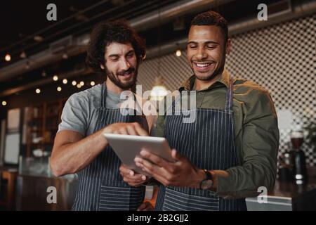 Multiethnic cafe co-workers working together in cafe using digital tablet Stock Photo