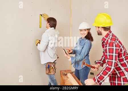 Female architect using tablet computer and handyman using tool while building house Stock Photo