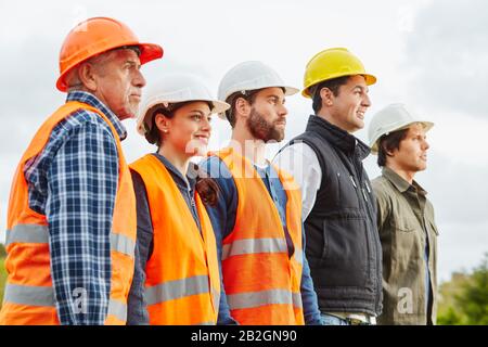 Construction workers and handyman team in a row with hard hat Stock Photo