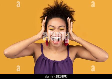 Happy black woman screaming and grabbing head Stock Photo