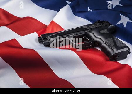 Handgun lying on American flag. Weapon problem concept Stock Photo