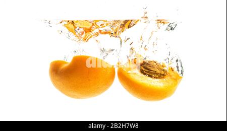 Fresh ripe peach split in half falling in the clear water Stock Photo