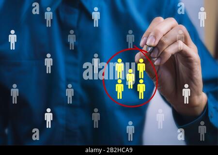 Teamwork or focus niche marketing concept. A businessman write a red line circle around yellow businessman icon. Stock Photo