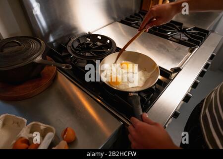 Young man cooking eggs on a pan Stock Photo