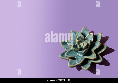 Blue lotus flower on violet background. Ceramic flower. Copy space. Stock Photo