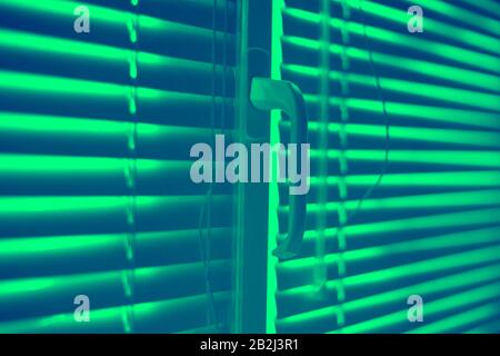 Closed horizontal blinds with rope and handle. Green toned. Stock Photo