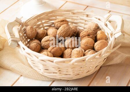 Walnut kernels and whole walnuts in basket on rustic old shabby wooden table Stock Photo