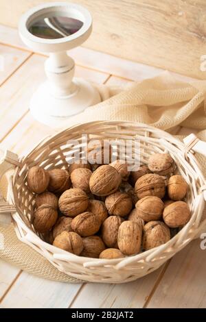 Walnuts with shells in white basket. Vertical vintage image Stock Photo