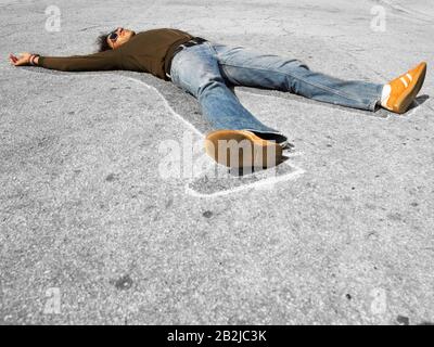 Chalk outline around dead victim lying in street Stock Photo