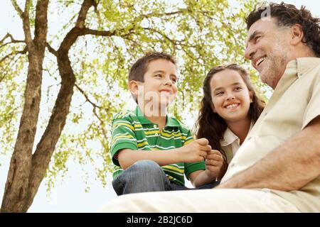 Boy (7-9) and girl (10-12) with grandfather low angle view. Stock Photo