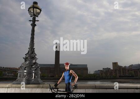Cyclist on bicycle standing by river embankment London England Stock Photo