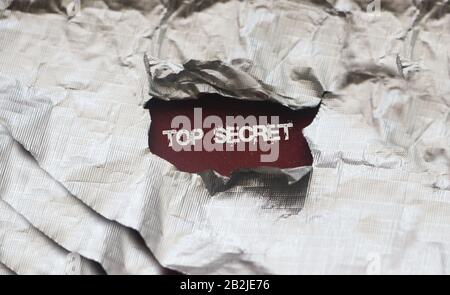 The words Top secret appearing behind torn foil Stock Photo