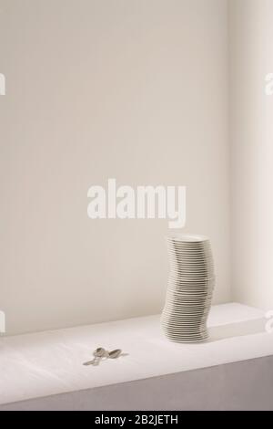 Spoons next to stack of plates on table Stock Photo
