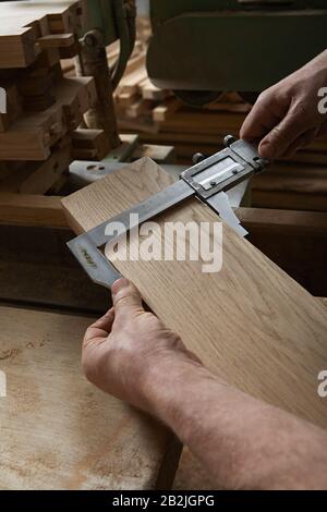 Carpenter Measuring Thickness of Wood Piece Stock Photo