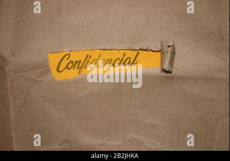 The word confidential appearing behind torn brown paper. Business concept Stock Photo