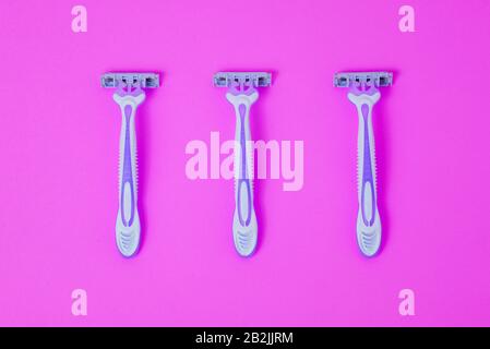 Razor for hair depilation. Body care. Three disposable razors on a pink background Stock Photo