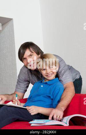 Portrait of a happy father helping son doing homework Stock Photo