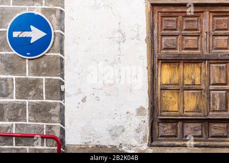 One way traffic sign on old wall next to wooden shuttered window in La Vera street in Guia de Isora, Tenerife, Canary Islands, Spain Stock Photo