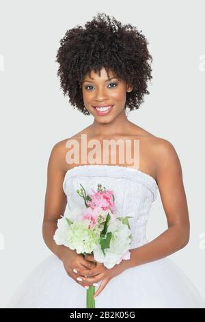 Portrait of an attractive African American bride holding bouquet over gray background Stock Photo