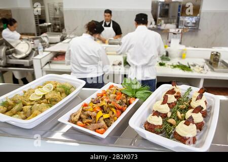 Close-up of foodstuff in serving dishes with chefs working in kitchen Stock Photo
