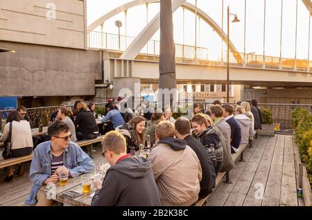 Young people drinking at a bar in Boxpark, Shoreditch, London, UK Stock Photo