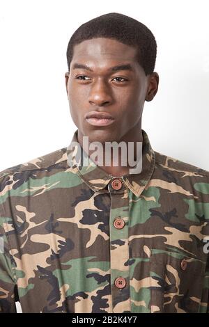 Thoughtful young military soldier in camouflage clothing looking away over white background Stock Photo