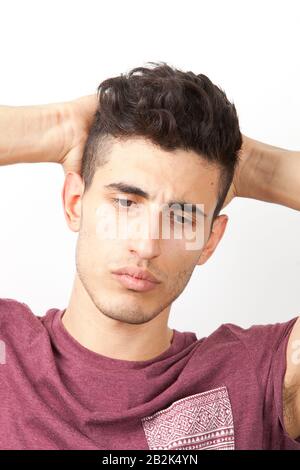 Pensive young Middle Eastern man with hands behind head over white background Stock Photo