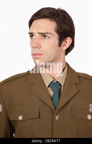 Thoughtful man in military uniform looking away against gray background Stock Photo