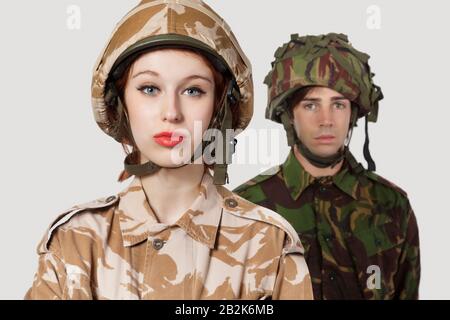 Portrait of young woman and man in military clothes against gray background Stock Photo