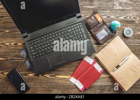 Preparing for an exciting journey. Booking flights and paying with a credit card using a laptop on a wooden background. The view from the top. Stock Photo