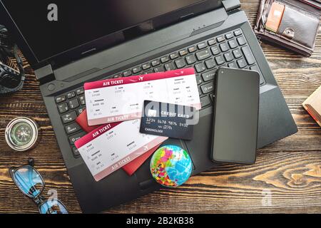 Preparing for an exciting journey. Booking flights and paying with a credit card using a laptop on a wooden background. The view from the top. Stock Photo
