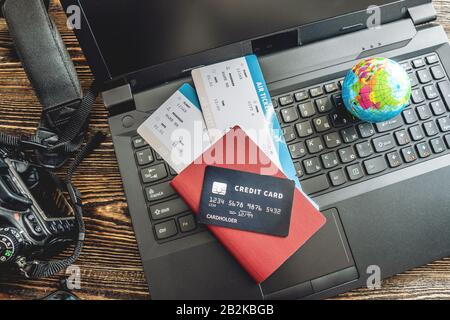 Preparing for an exciting journey. Booking flights and paying with a credit card using a laptop on a wooden background. The view from the top. Stock Photo