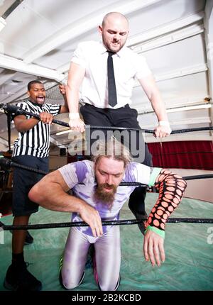 Wrestlers fighting while referee counting during match Stock Photo