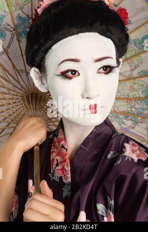 Close-up of Japanese woman with painted face holding parasol Stock Photo