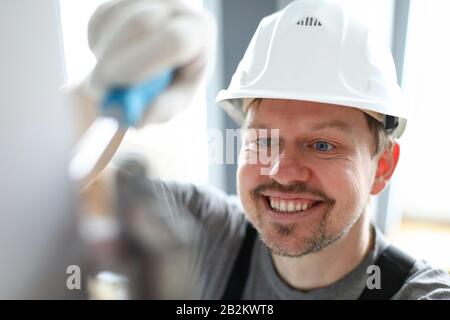 Young repairman in helmet, gloves and special uniform repairing house details Stock Photo
