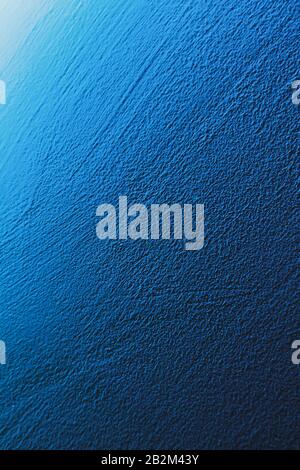 Textured aqua blue painted wall background and texture. The wall is illuminated with cyan light. Grain shows. Stock Photo