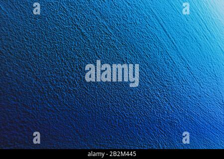 Textured aqua blue painted wall background and texture. The wall is illuminated with cyan light. Grain shows. Stock Photo