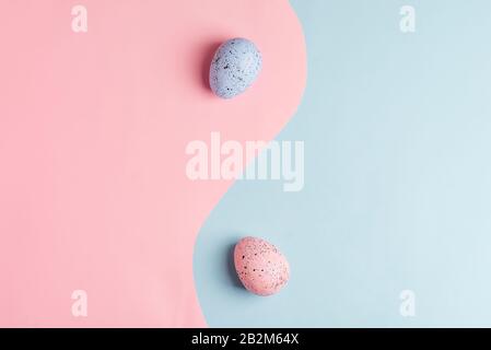 Creative composition from two handmade painted Easter eggs on a duotone pastel pink blue background as a symbol of infinity, copy space. Top view. Hap Stock Photo