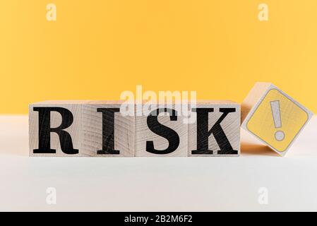 word RISK and risk symbol with exclamation mark on wooden cubes against orange background Stock Photo