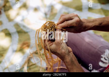 Female weaving basket on the craft workshop. Hands holding the craftwork, close up shot. Stock Photo