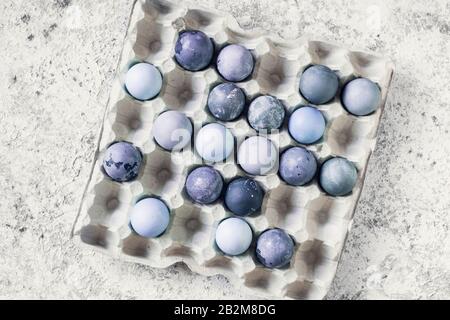 Blue Easter eggs with marble stone effect on grey concrete background. Row of ombre blue Easter eggs. Natural ecological staining with food coloring. Stock Photo